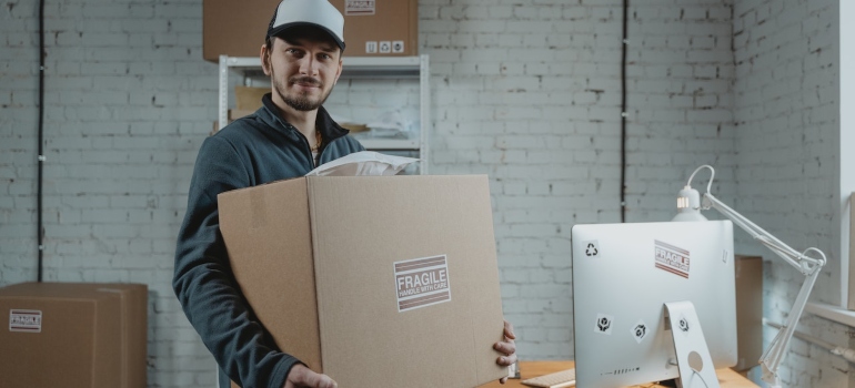 a moving crew personnel holding a large box labelled as fragile