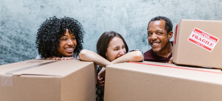 friends behind moving boxes laughing 