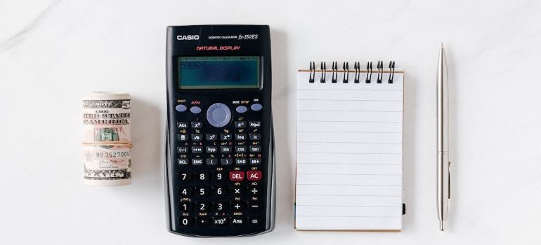 a calculator, a notebook, pen and paper money next to each other