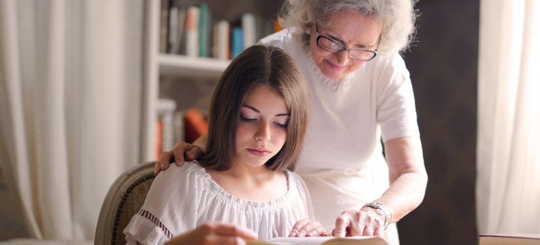 A granny helping her granddaughter read about the reasons to move to NB as a senior