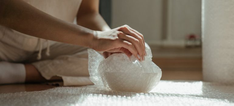 Woman packing a vase in bubble wrap and thinking about the 7 things to remember when moving from Texas to NJ