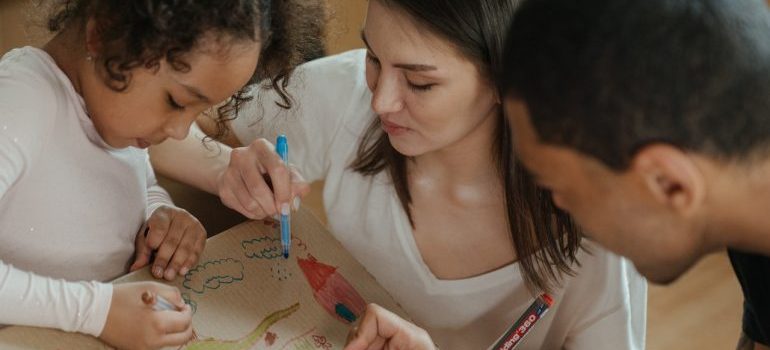 Los padres de la joven de dibujo en cajas de mudanza con su hija, sé todo acerca de mudanza de larga distancia en Texas con los niños