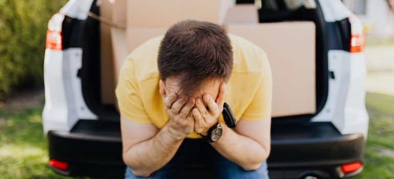 Stressed man sitting on the trunk of a car