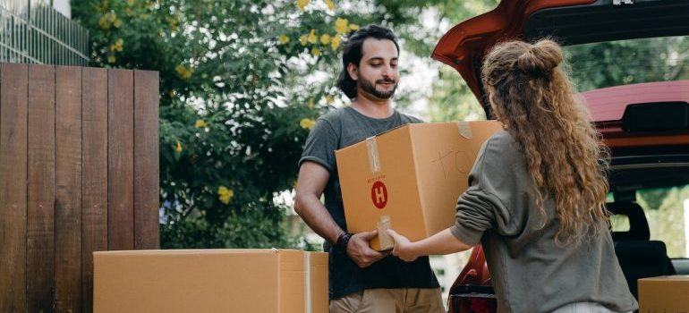 Pareja cargando cajas en un vehículo antes de la mudanza de larga distancia en coche 