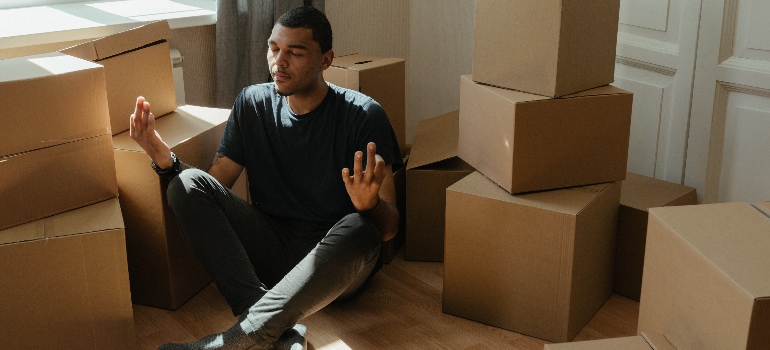 a man meditating next to the moving boxes 