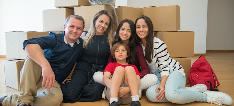 Una familia en la posición de sentado en frente de las cajas de mudanza 