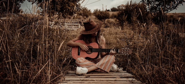 A woman playing a guitar after moving from NC to Texas