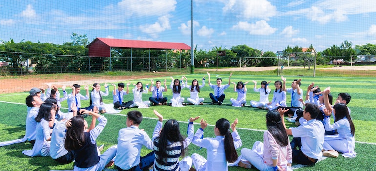 Children sitting on school football filed