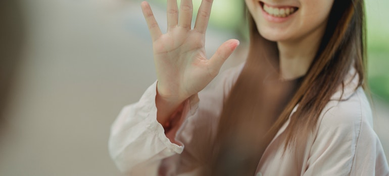 Sonriente mujer dice adiós con la mano