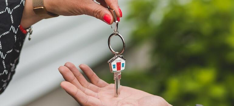 a person handing keys to another person can help you buy a home in Dallas right now