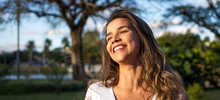 una mujer sonriente en el parque saber cómo mudanzas interestatales afecta a la salud mental