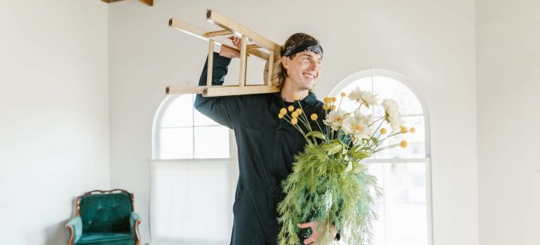 A man carryuing a chair and a plant