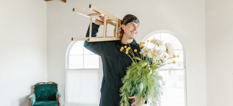 Un hombre carryuing una silla y una planta