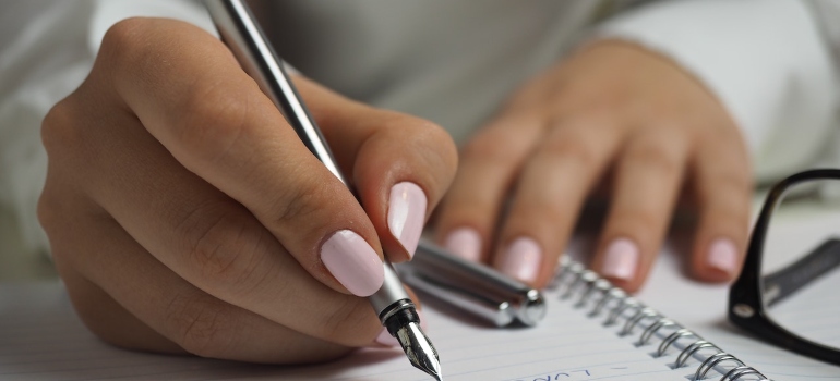 a person with white nails writing on paper 