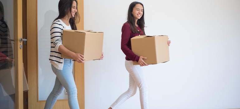 two girls carrying boxes