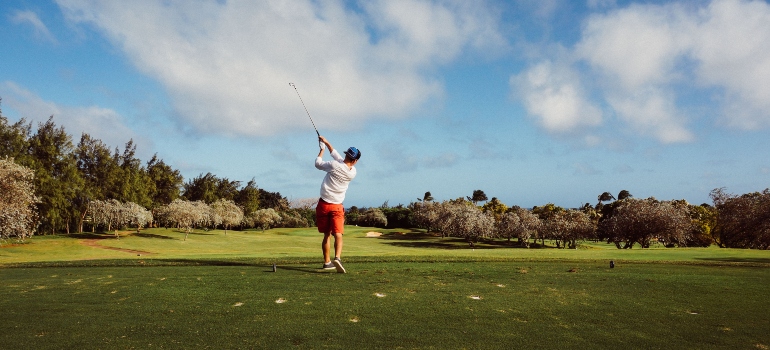 A man in a white t-shirt playing golf before moving to Round Rock