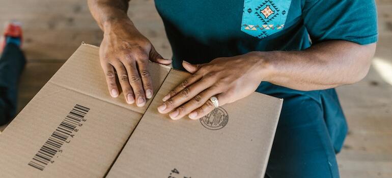 A person closing a box after organizing a Bellaire relocation around the holidays