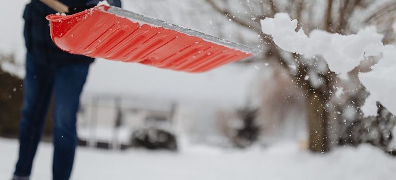 a person shoveling snow wondering about the tips to move out of state during winter