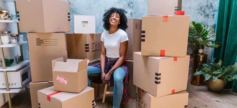 A girl sitting between boxes before moving out of state from Houston Heights