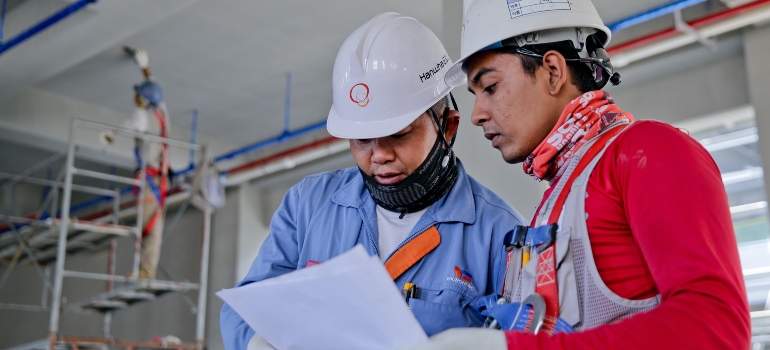 dos trabajadores de la construcción, buscando en los planes de