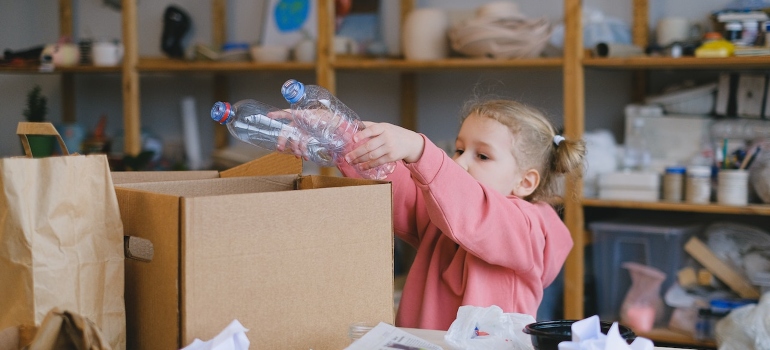 una niña de poner botellas de plástico en una caja 