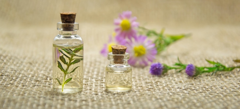 Picture of two small glass bottles next to purple flowers 