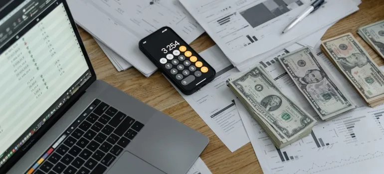 laptop, phone, papers and money on the table 
