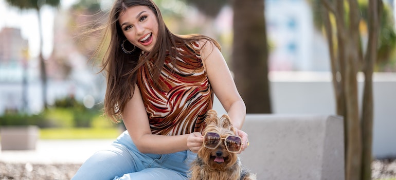 Laughing Woman Sitting on a Bench with her Dog Wearing Sunglasses.