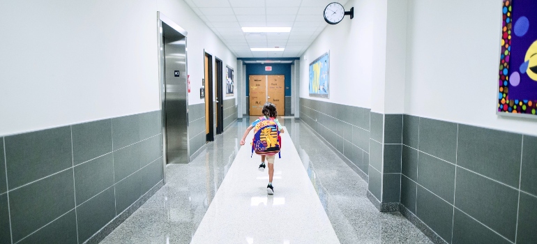 Un niño en la escuela que se ejecuta en el pasillo