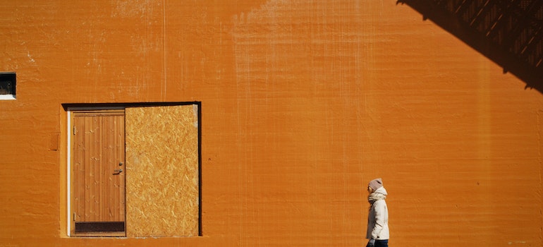 A person is next to the orange wall.