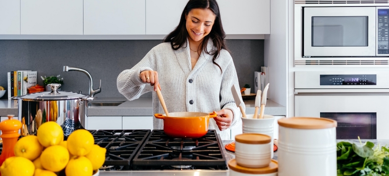 Una mujer de cocción en el interior de la cocina, la sala y el pensamiento acerca de los factores para reinventarse a sí mismo y a su carrera 