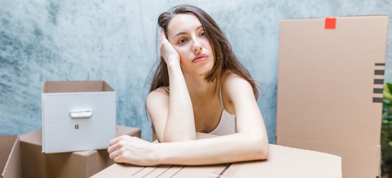 a worried woman surrounded by moving boxes