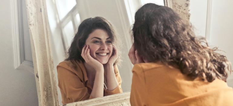 a woman smiling at her reflection in the mirror