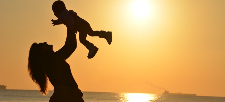 una mujer sostiene a su hijo en la puesta de sol en una playa