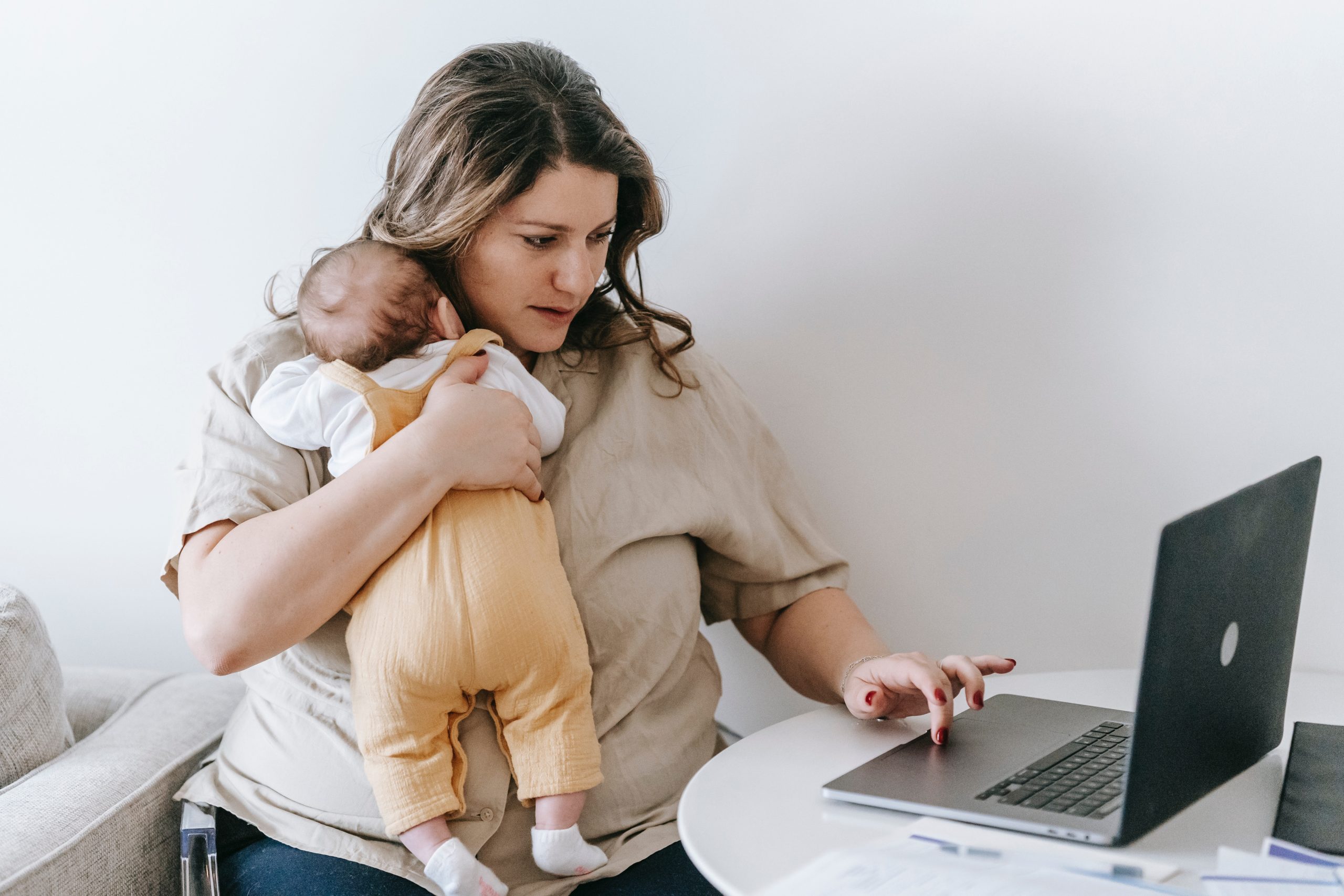 una mujer sosteniendo a un bebé mientras está tratando de trabajar