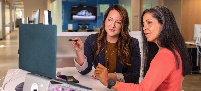 two women looking at a computer screen 