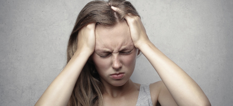 a woman having a headache while trying to avoid moving scams when leaving Texas