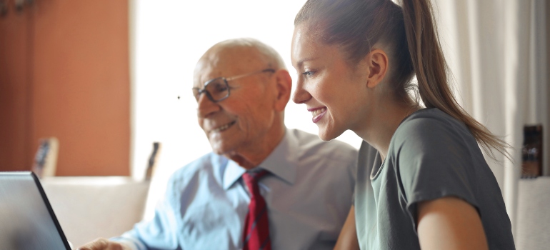 a young woman and her grandfather looking at a computer screen