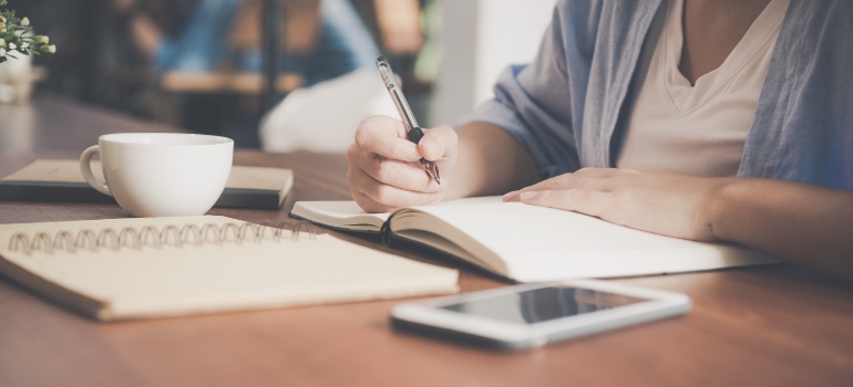 una mujer escribiendo algo en un cuaderno acerca de mejoras en el hogar que requieren un permiso en Dallas